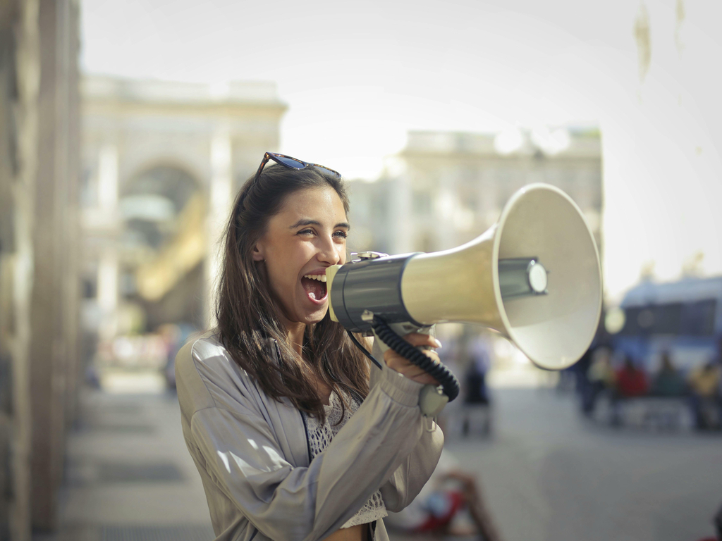 Foto door Andrea Piacquadio: https://www.pexels.com/nl-nl/foto/vrolijke-jonge-vrouw-die-in-megafoon-gilt-3761509/